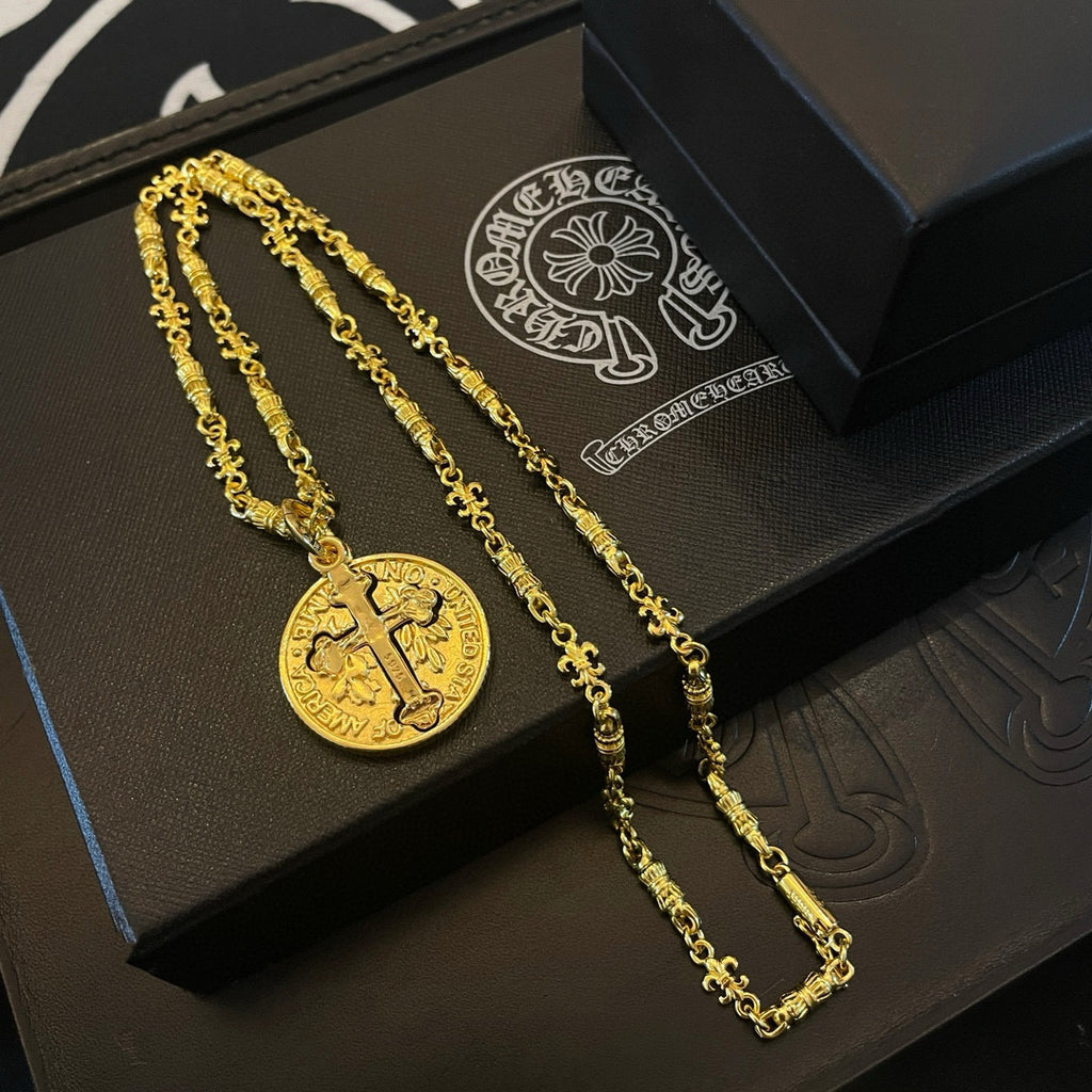 Gold-tone cross pendant necklace and chain on black gift tray, multiple pieces.
