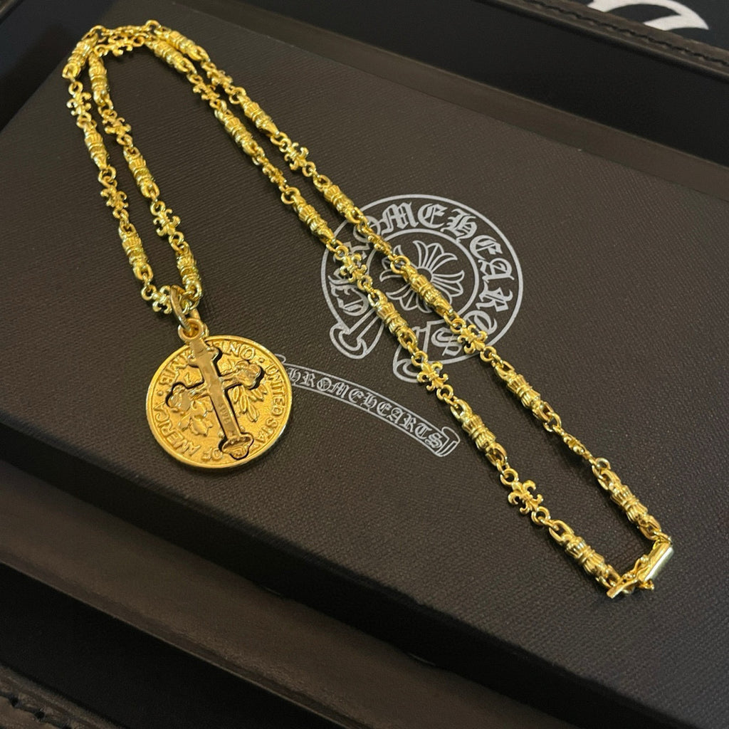 Gold-tone cross pendant necklace set on black display tray, two chains shown.