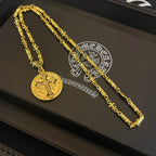 Gold-tone cross pendant necklace set on black display tray, two chains shown.