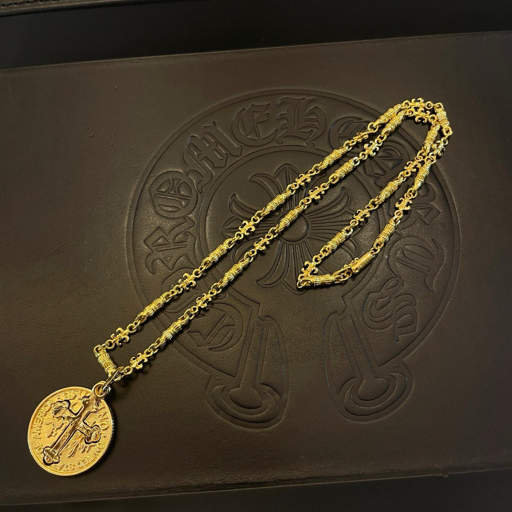 Gold-tone cross pendant necklace with round pendant and textured chain on black box.