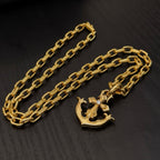 Gold-tone anchor pendant necklace with curb-link chain, laid out