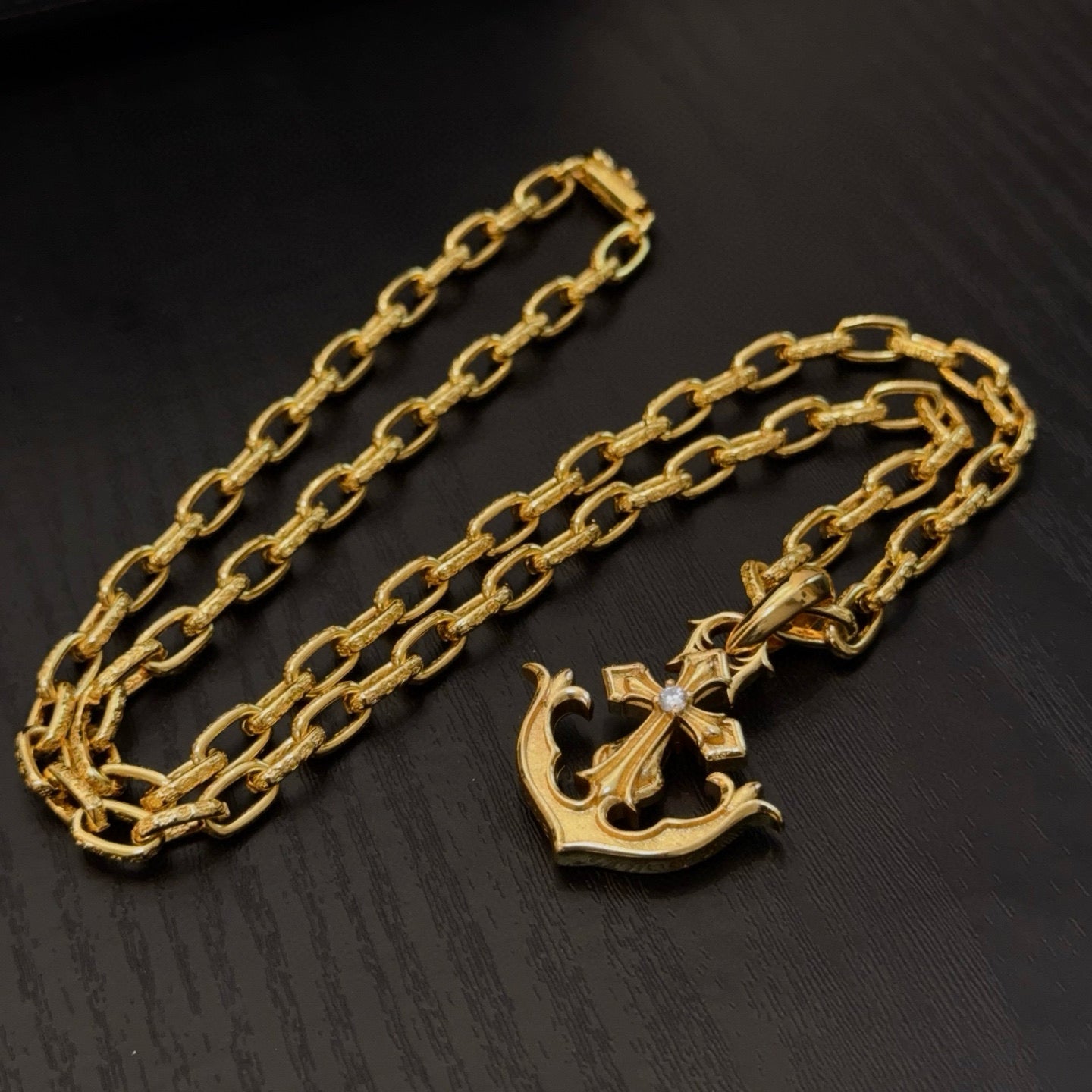 Gold-tone anchor pendant necklace with curb-link chain, laid out