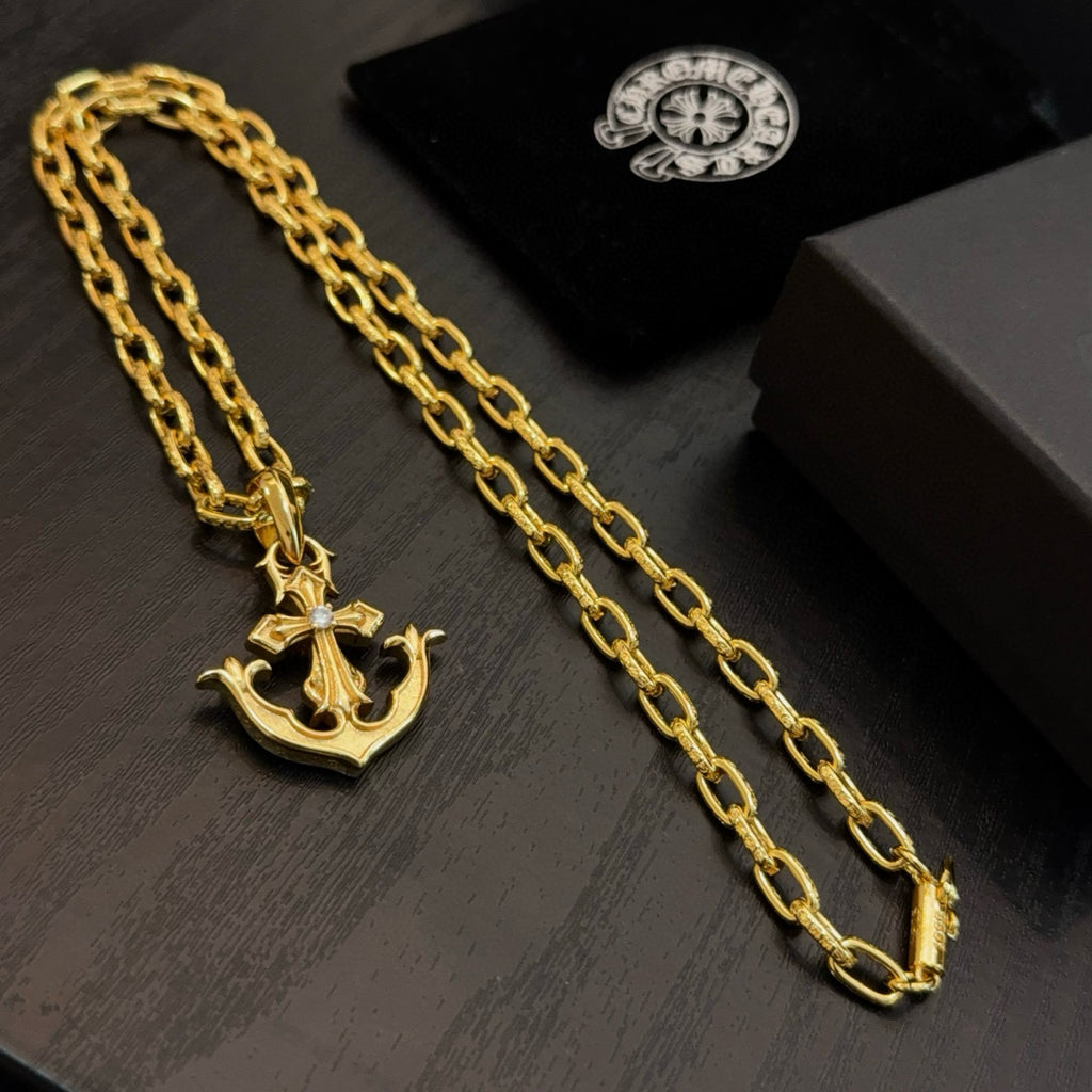 Gold-tone necklace with crown and anchor pendants on curb-link chain