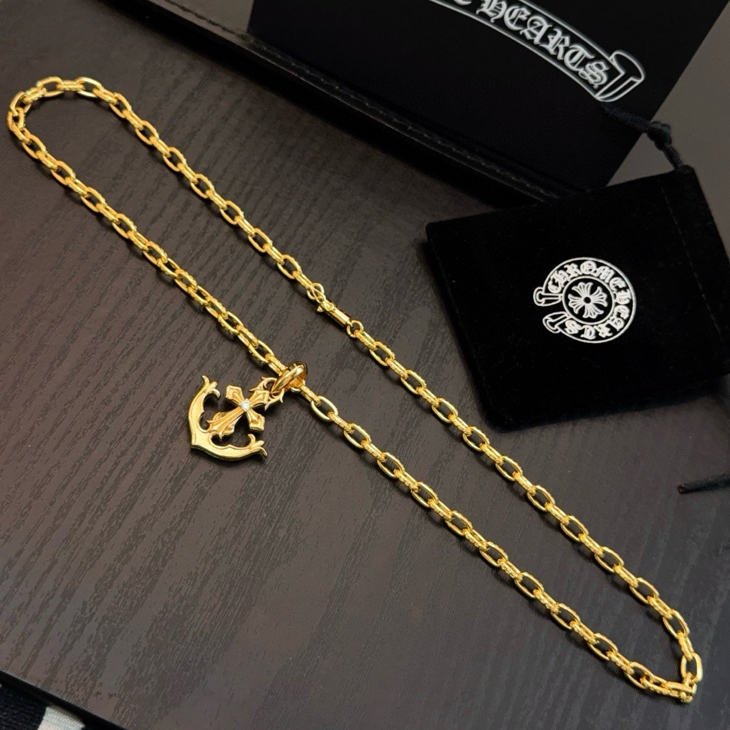 Gold-tone anchor pendant necklace with curb-link chain, laid flat