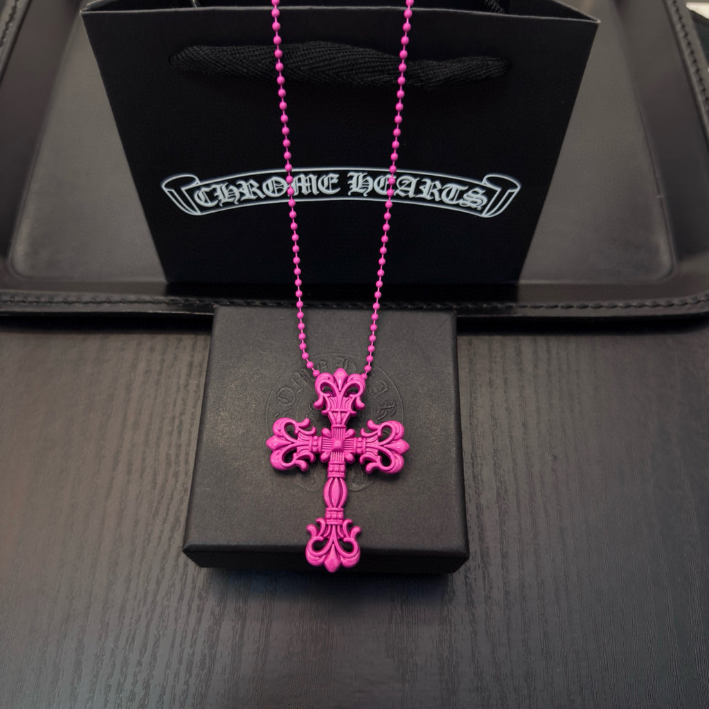 Pink beaded cross necklace with floral cross pendant, displayed in a jewelry box