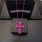 Pink beaded cross necklace with floral cross pendant, displayed in a jewelry box