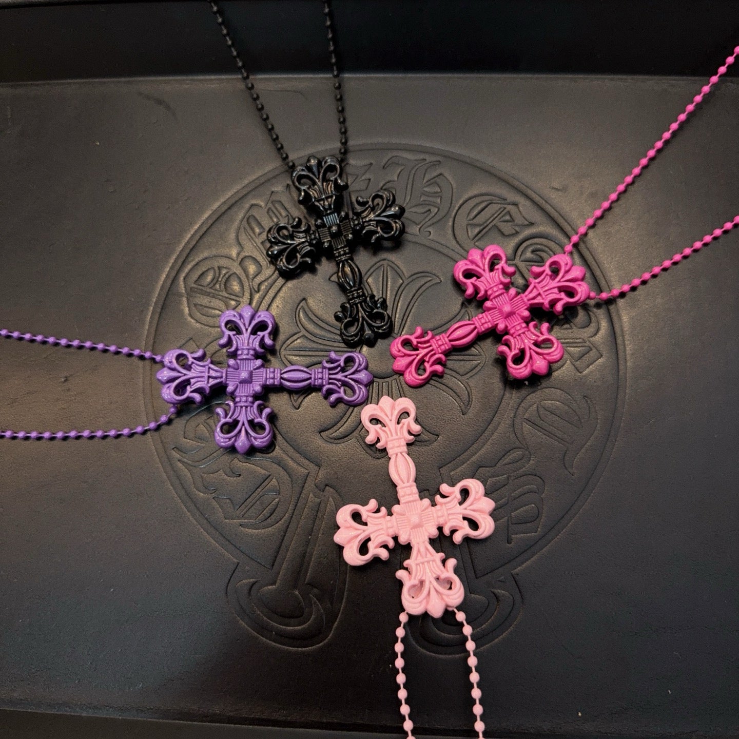 Layered bead necklaces with cross pendants in pink, purple, and black tones
