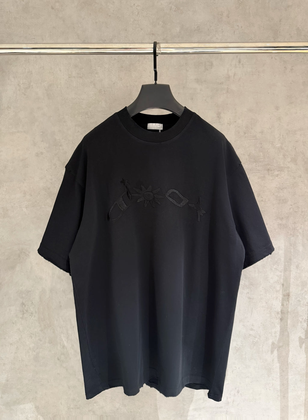 Black short-sleeve T-shirt with crew neck and embroidered graphic on chest.