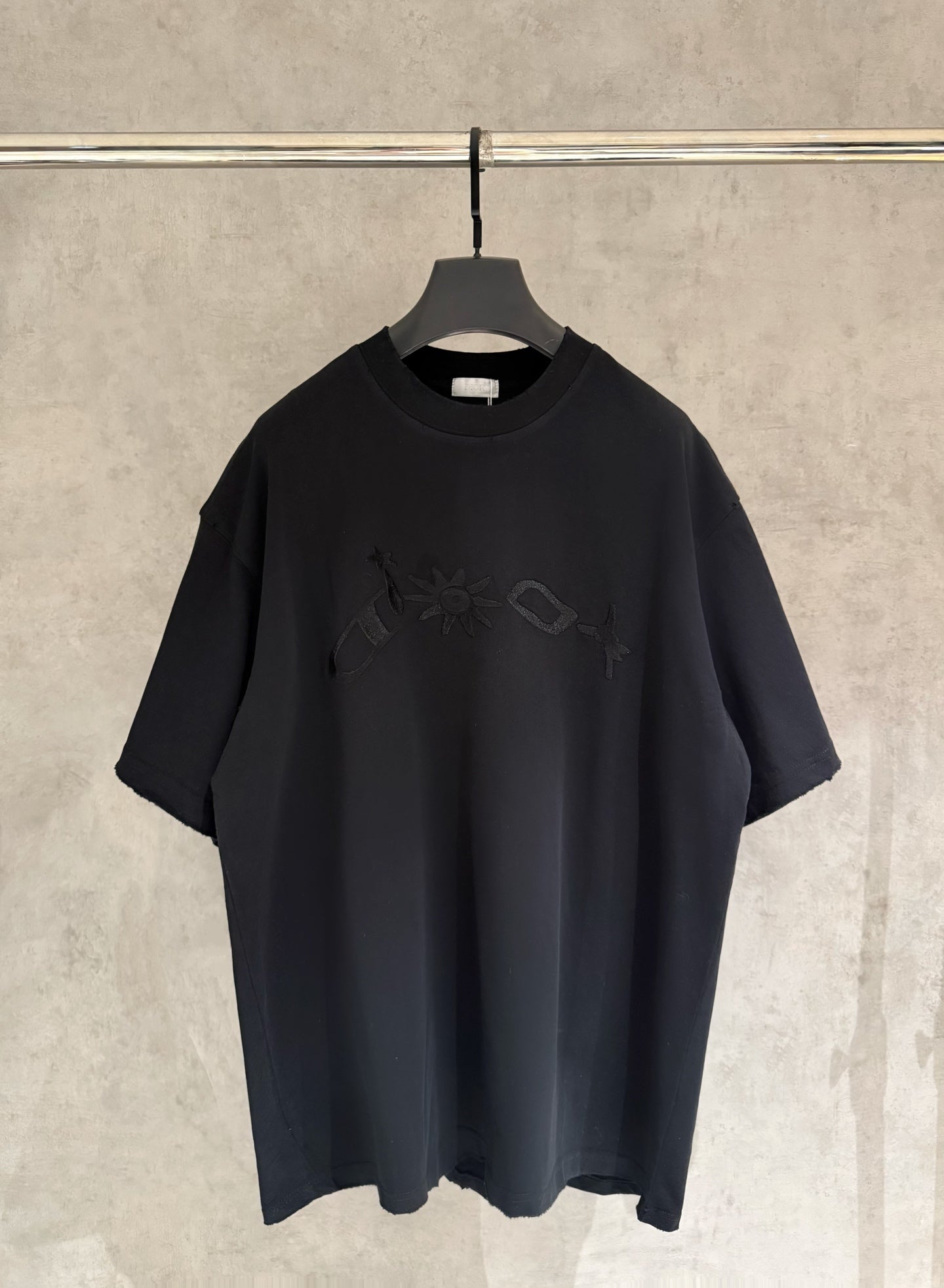 Black short-sleeve T-shirt with crew neck and embroidered graphic on chest.