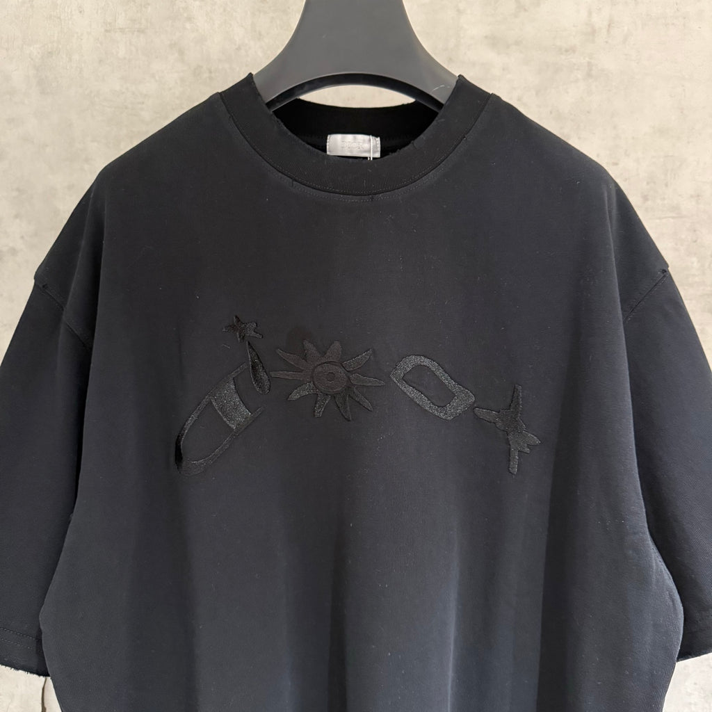 Black crew-neck T-shirt with front embroidered graphic near neckline.