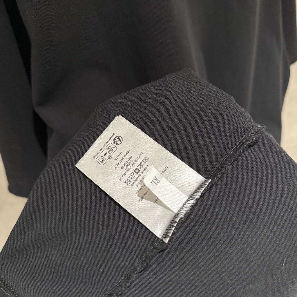 Black T-shirt care label on inner sleeve seam.