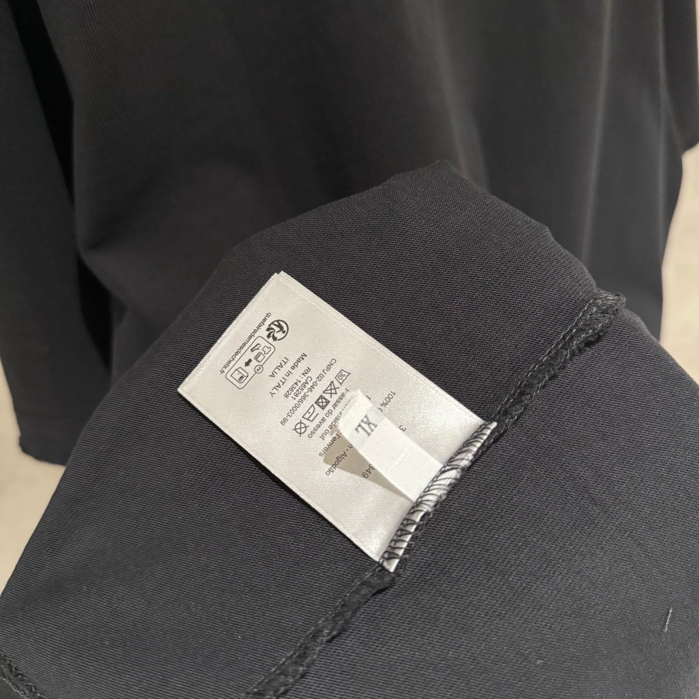 Black T-shirt care label on inner sleeve seam.