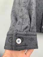 Monogram button-up shirt cuff close-up with gold-trimmed snap button