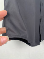 Long-sleeve button-up shirt, dark gray, hand-held view of side hem and seam