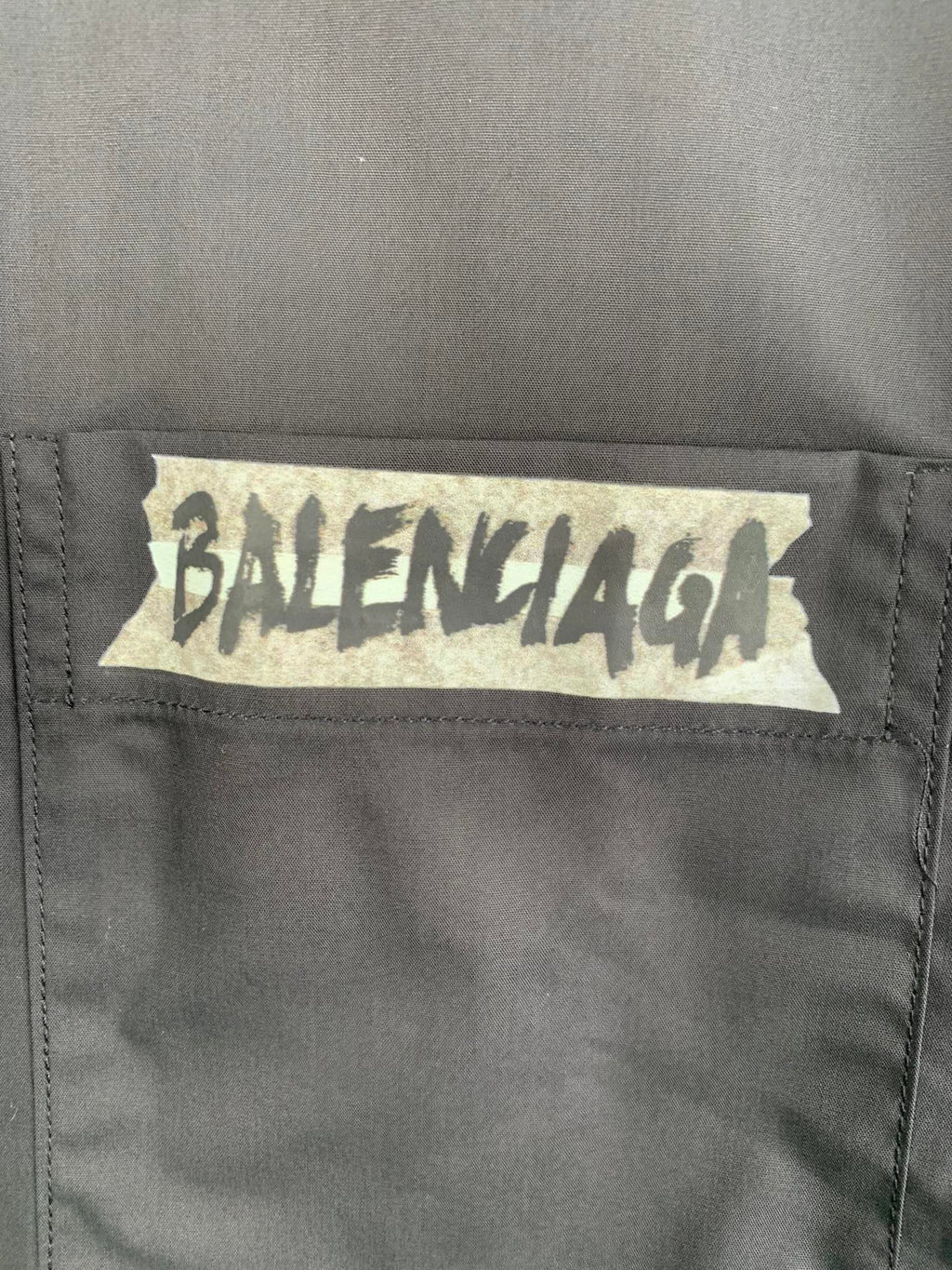 Long-sleeve button-up shirt, gray, close-up of front logo patch