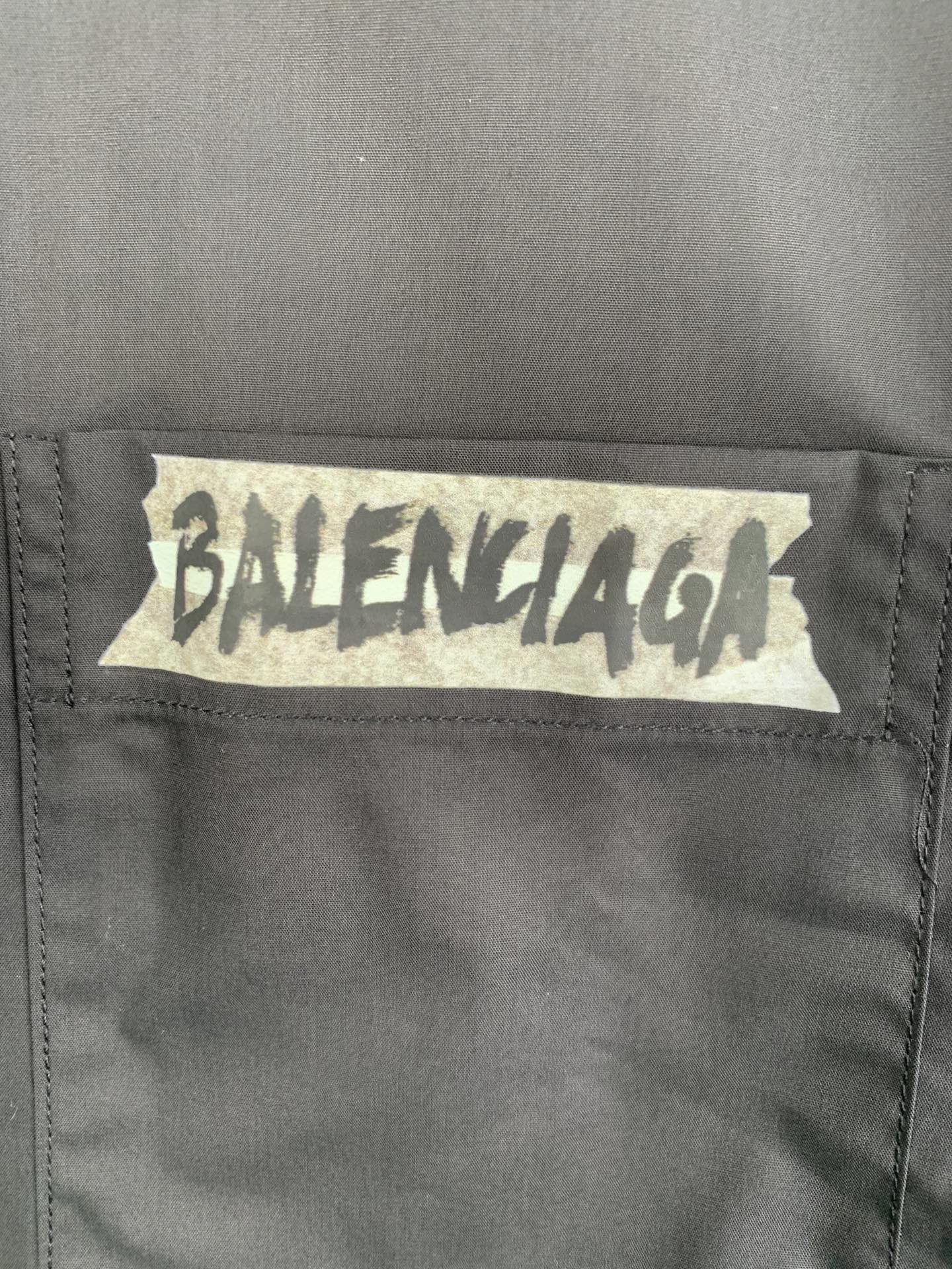 Long-sleeve button-up shirt, gray, close-up of front logo patch
