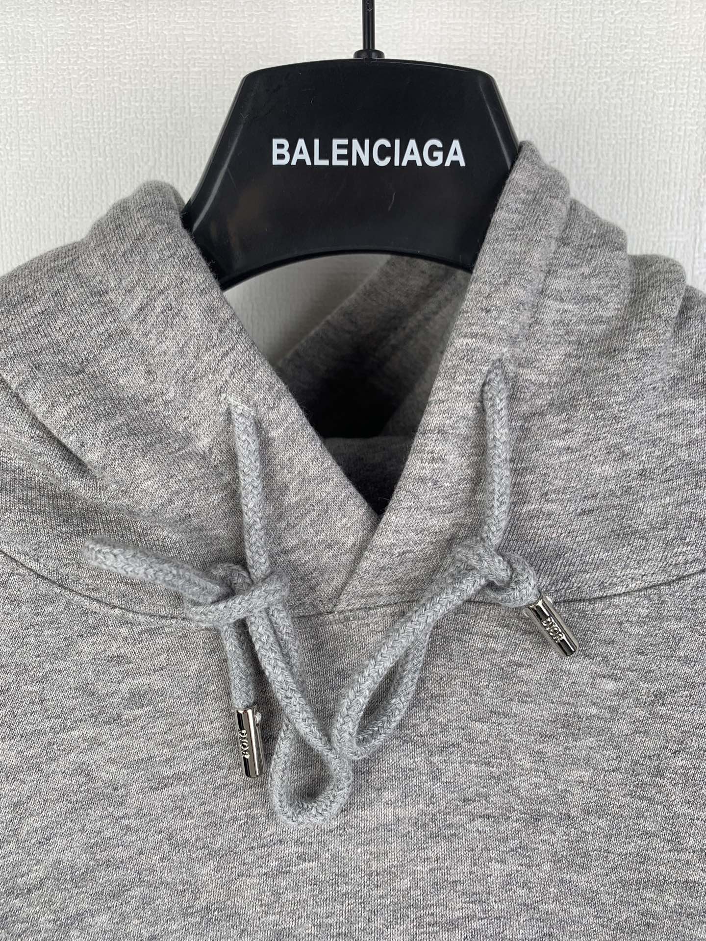 Gray hoodie hood with white drawstrings and metal tips, Dior logo