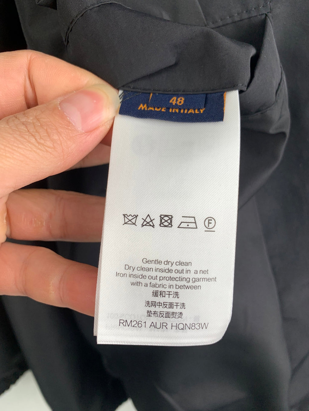 Clothing care label tag showing size 48 and Louis Vuitton, RM261 AUR HQN83V