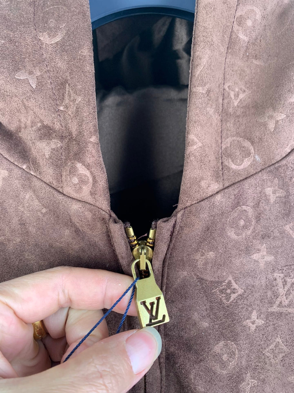 Dark brown monogram hooded jacket zipper pull with gold hardware and fabric tag