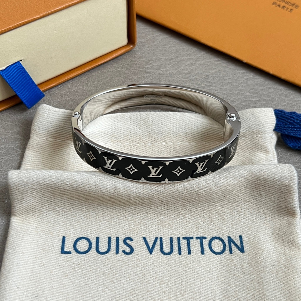 Louis Vuitton black monogram bangle with silver links on cream pouch, top view