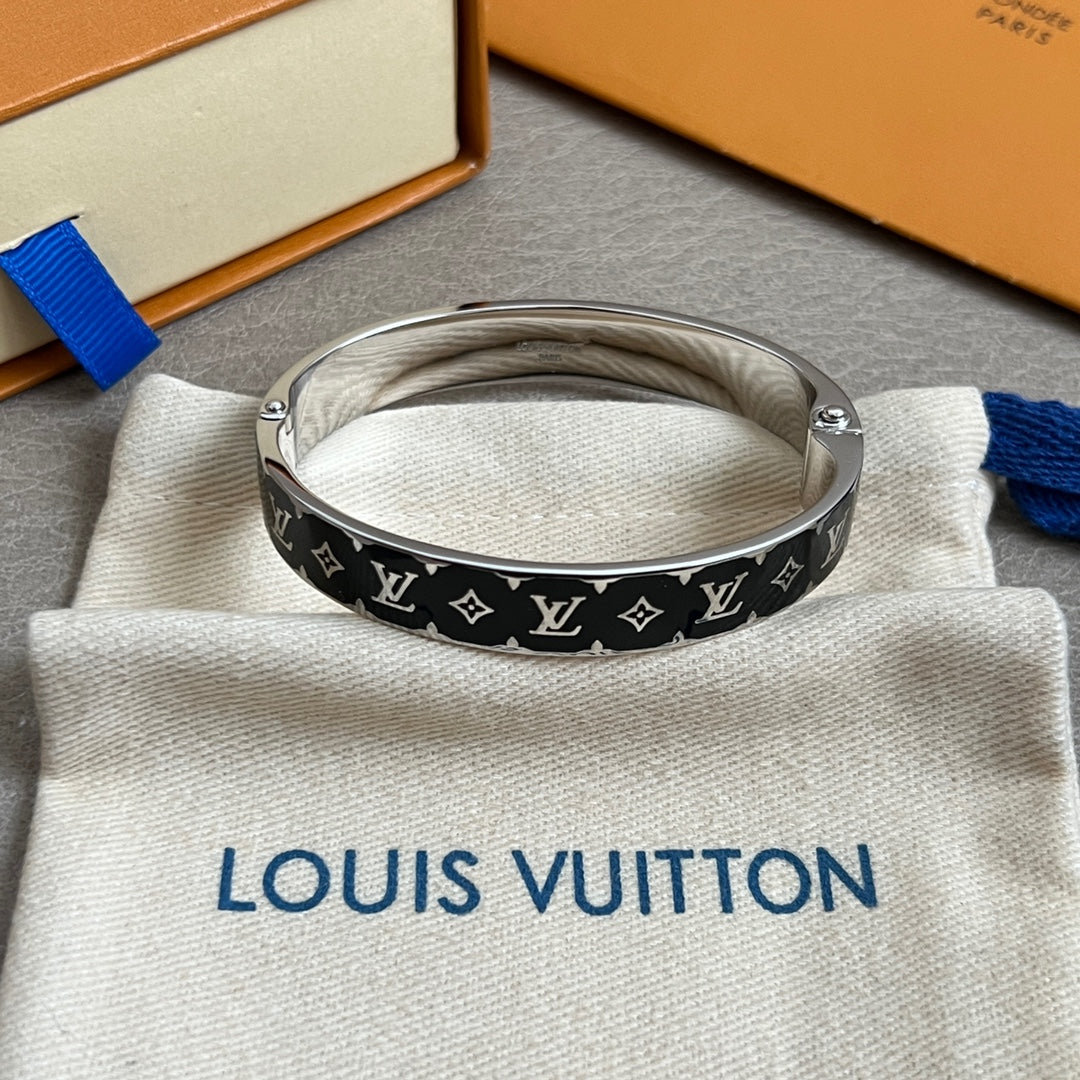 Louis Vuitton black monogram bangle with silver links on cream pouch, top view