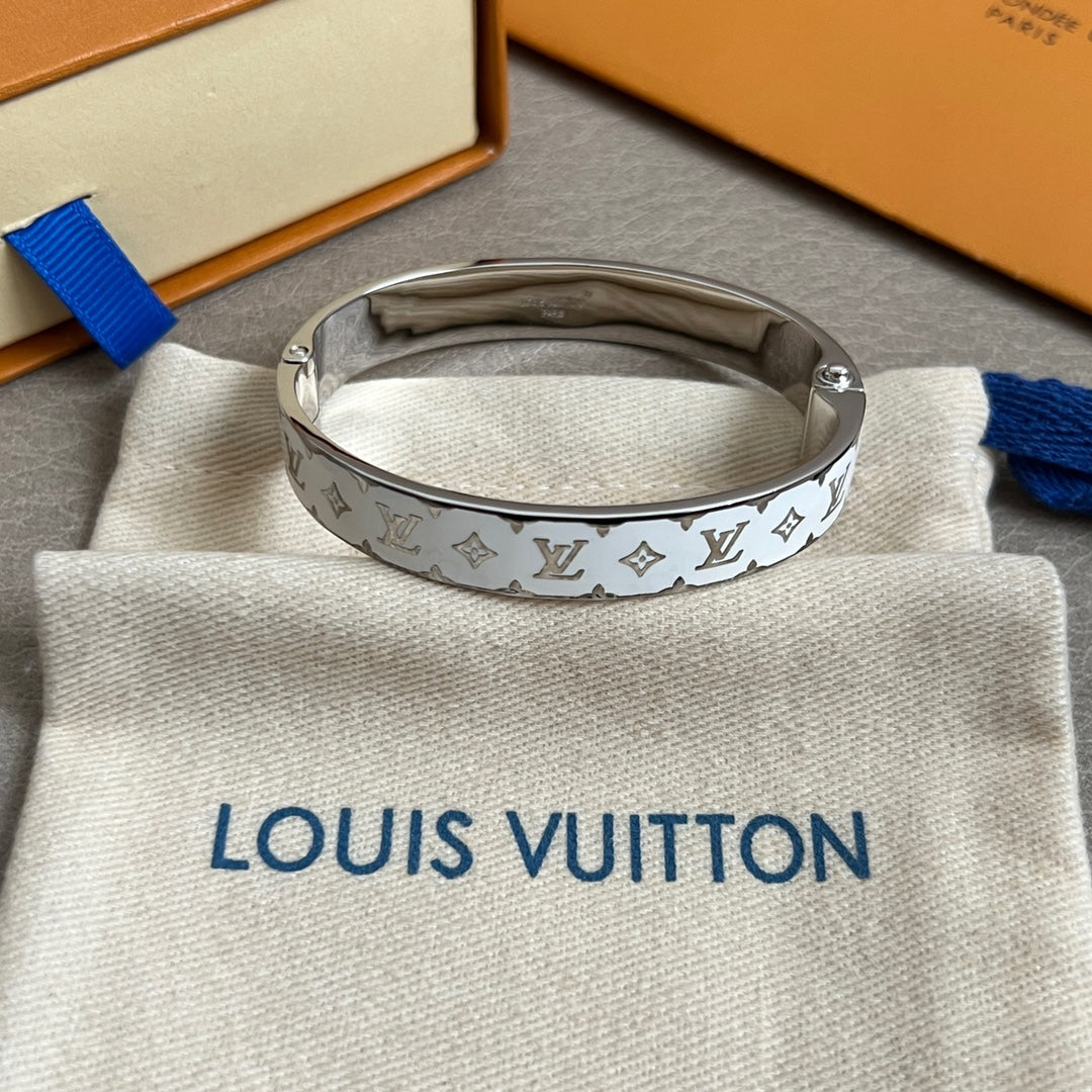 Silver Louis Vuitton cuff bracelet with LV monogram pattern, bracelet interior visible