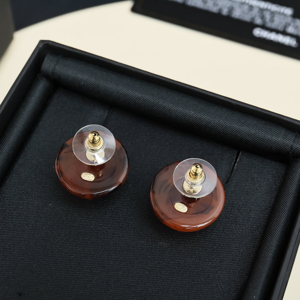 Brown round stud earrings with gold-tone posts and Chanel CC logo, close-up pair