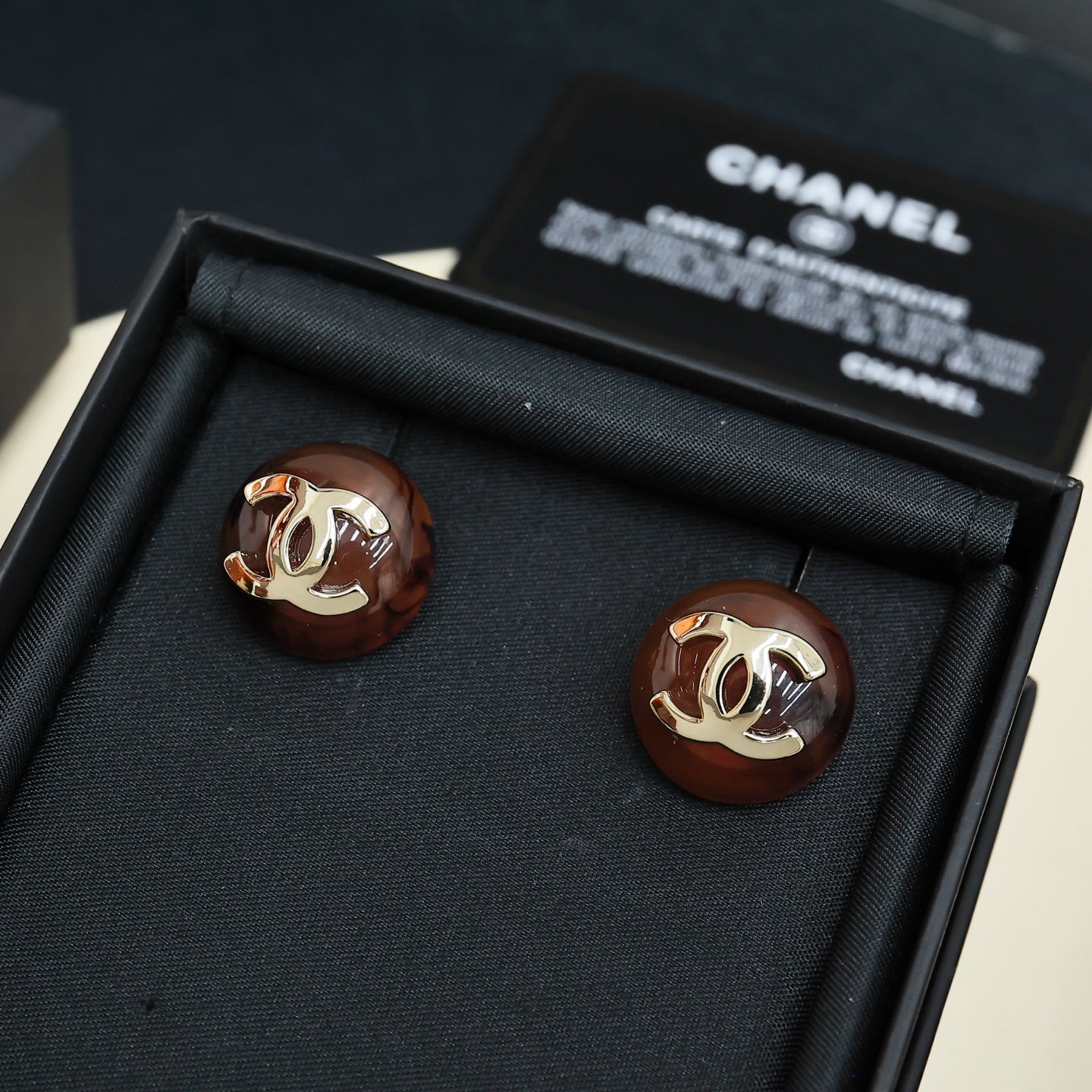 Brown round stud earrings with gold-tone Chanel CC logo, pair in black gift box