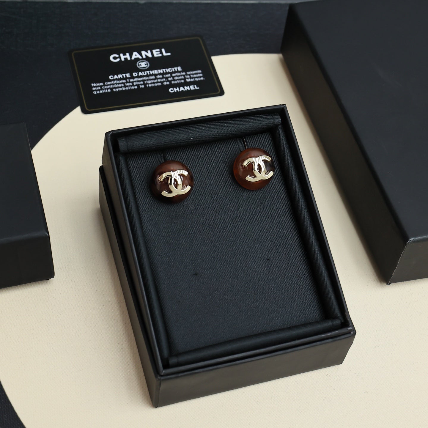 Brown round stud earrings in black presentation box with Chanel card