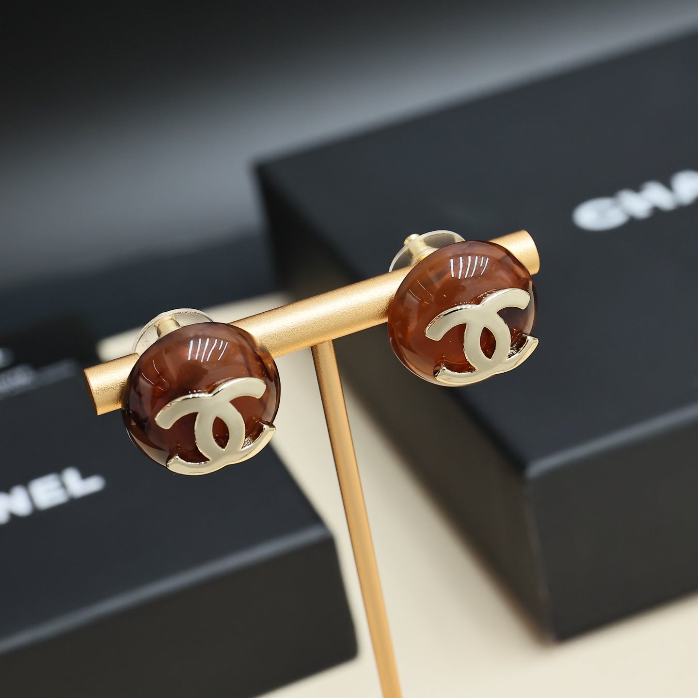 Brown round stud earrings with gold-tone Chanel CC logos on a gold holder
