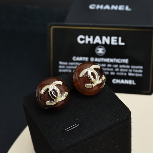 Brown round stud earrings with gold-tone Chanel CC logos, pair on black cushion
