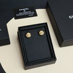 Gold-tone stud earrings presented in a black jewelry box