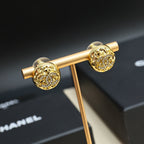 Gold-tone stud earrings with round logo face on a display stand