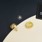 Gold-tone round stud earrings with decorative logo motif and rhinestone center
