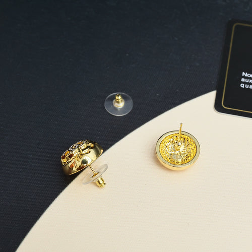 Gold-tone round stud earrings with decorative logo motif and rhinestone center