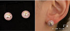 Chanel stud earrings on ear: round pink enamel with gold-tone CC logo