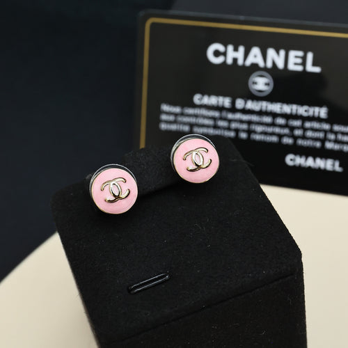 Chanel stud earrings with round pink enamel, gold-tone CC monogram, on black card