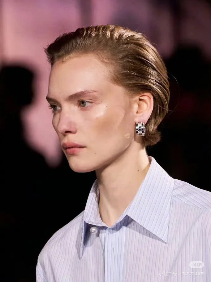 Gold-tone rhinestone hoop earrings worn by model on the ear