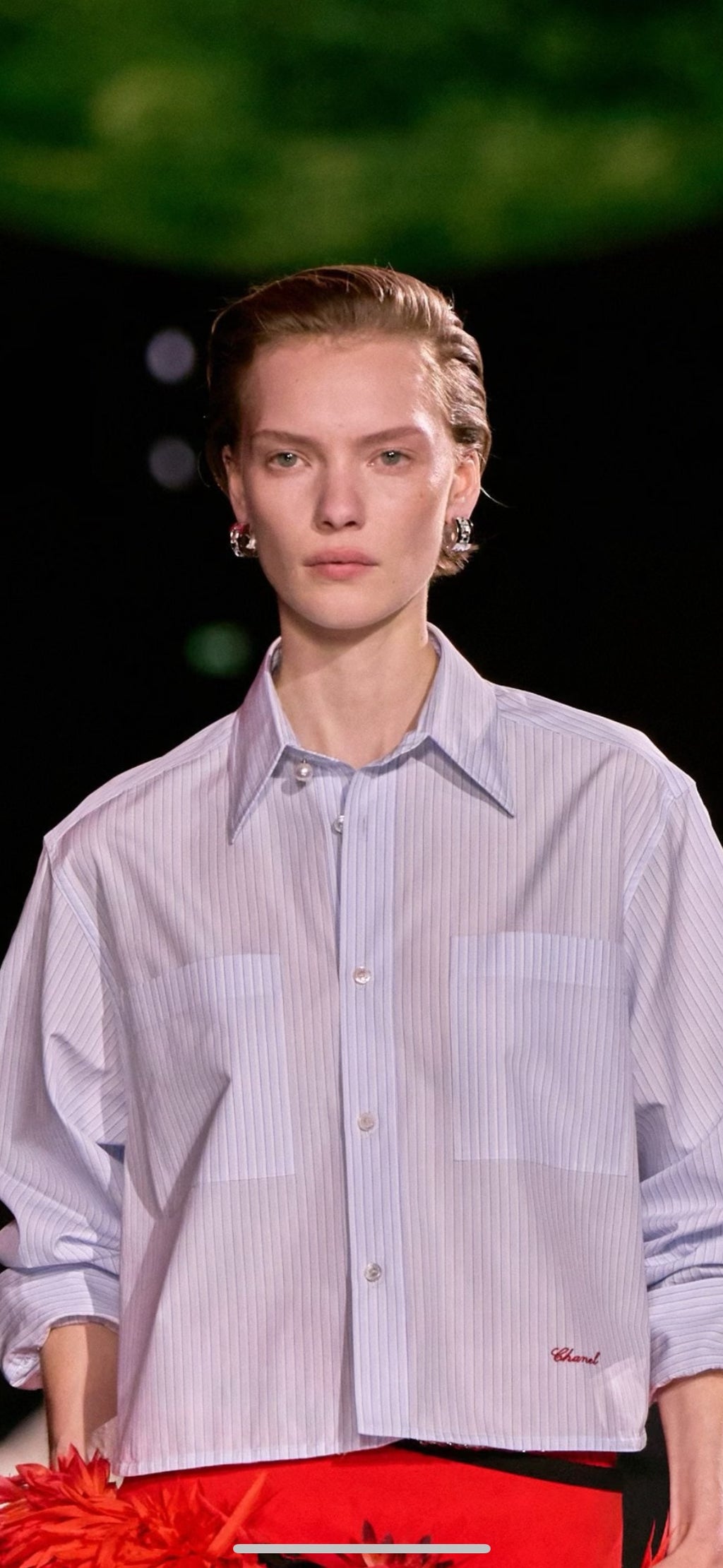 Gold-tone hoop earrings with clear rhinestones on the ear, styled with an outfit