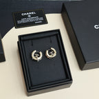 Gold-tone hoop earrings with logo medallion and clear rhinestone accents in box