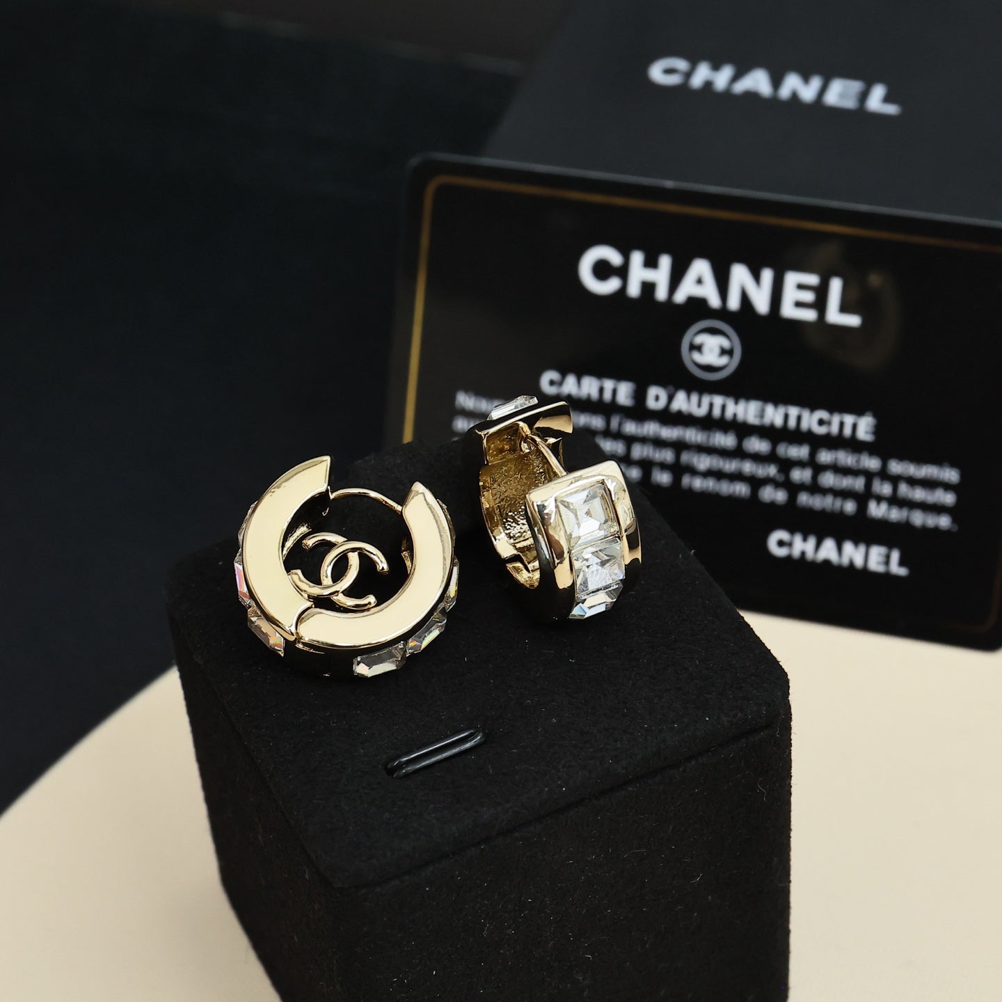 Gold-tone hoop earrings with interlocking logo and clear rhinestone accents