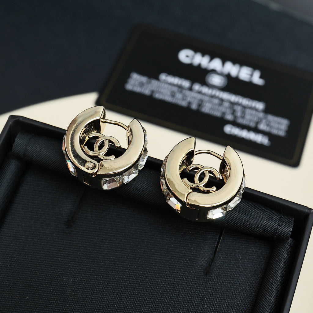 Gold-tone hoop earrings with interlocking logo center and clear stone embellishments