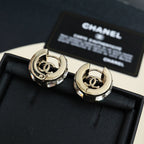Gold-tone hoop earrings with interlocking logo center and clear stone embellishments
