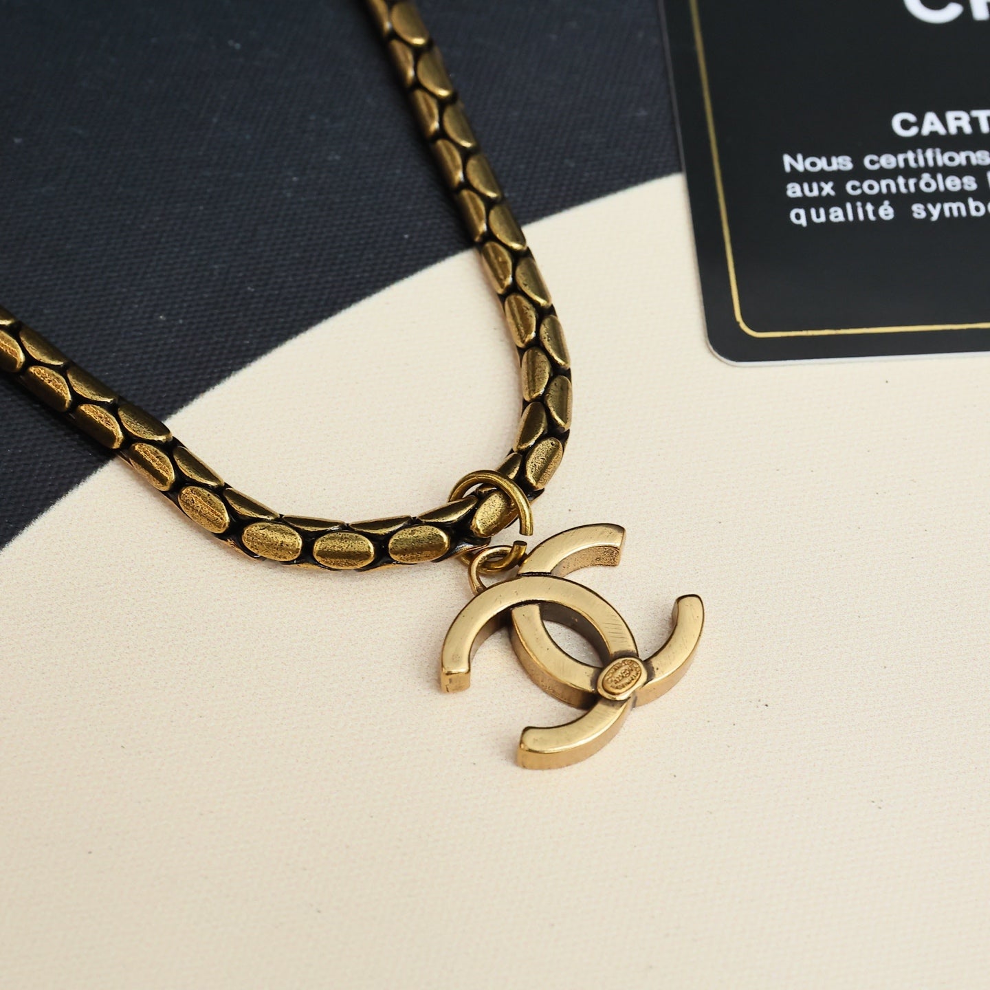 Close-up of gold-tone link chain necklace with Chanel logo charm