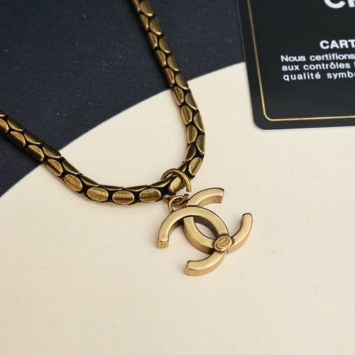 Close-up of gold-tone link chain necklace with Chanel logo charm