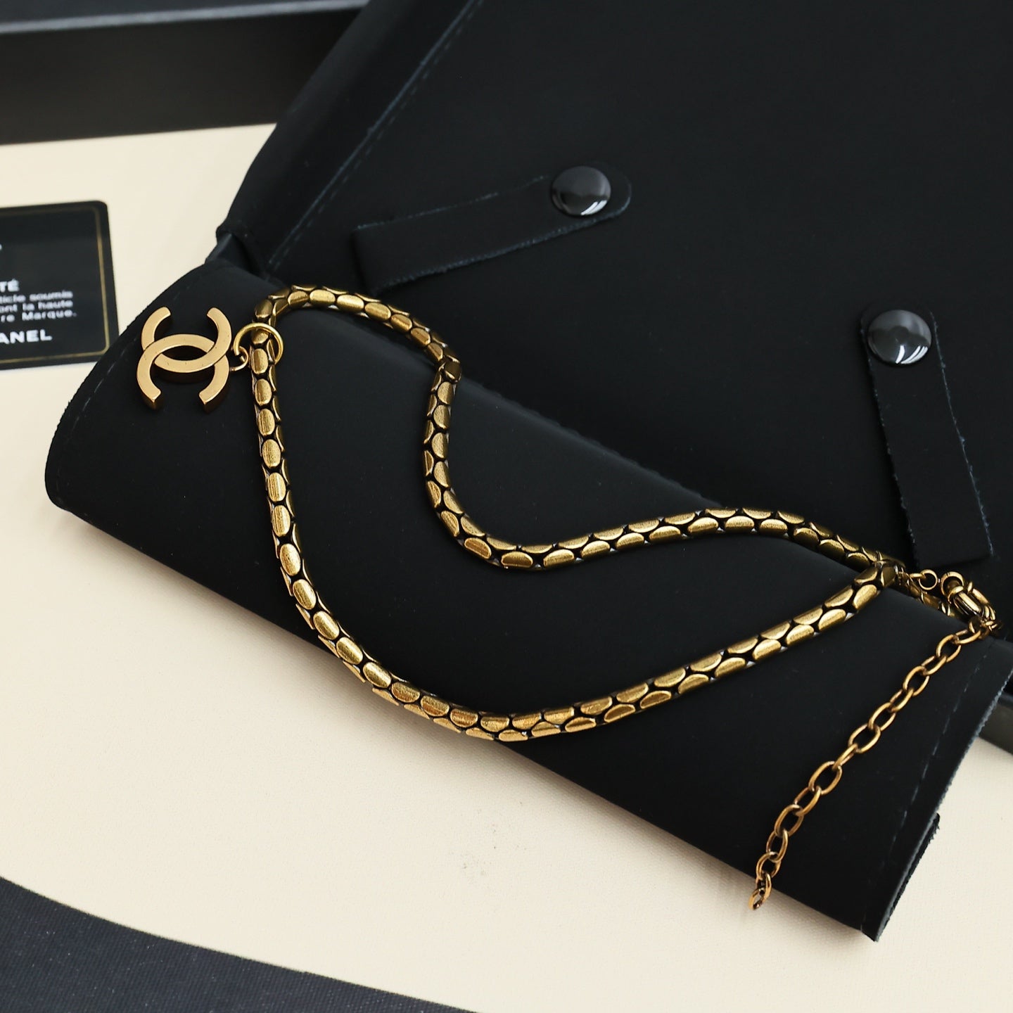 Gold-tone Chanel logo link chain necklace on black pouch