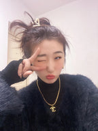 Gold-tone Chanel logo chain necklace worn by person