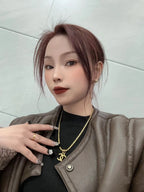 Gold-tone Chanel logo chain necklace worn with black top