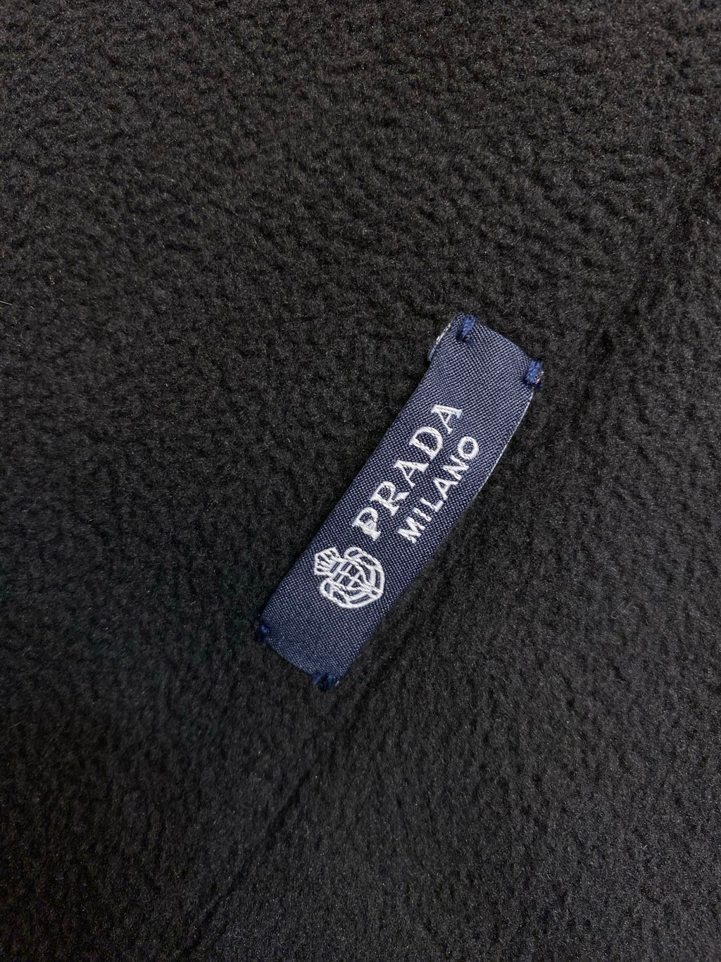 Prada Milano fabric label on dark textured fleece material
