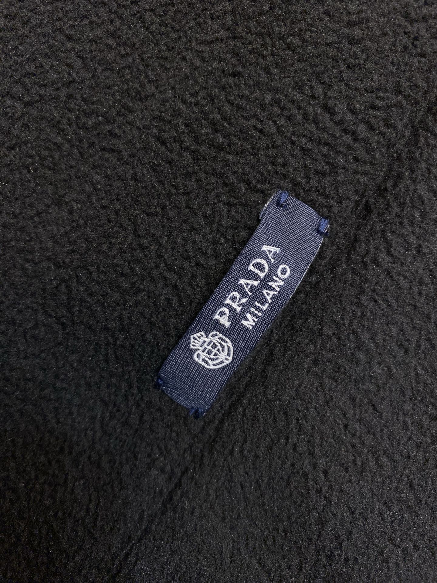 Prada Milano fabric label on dark textured fleece material